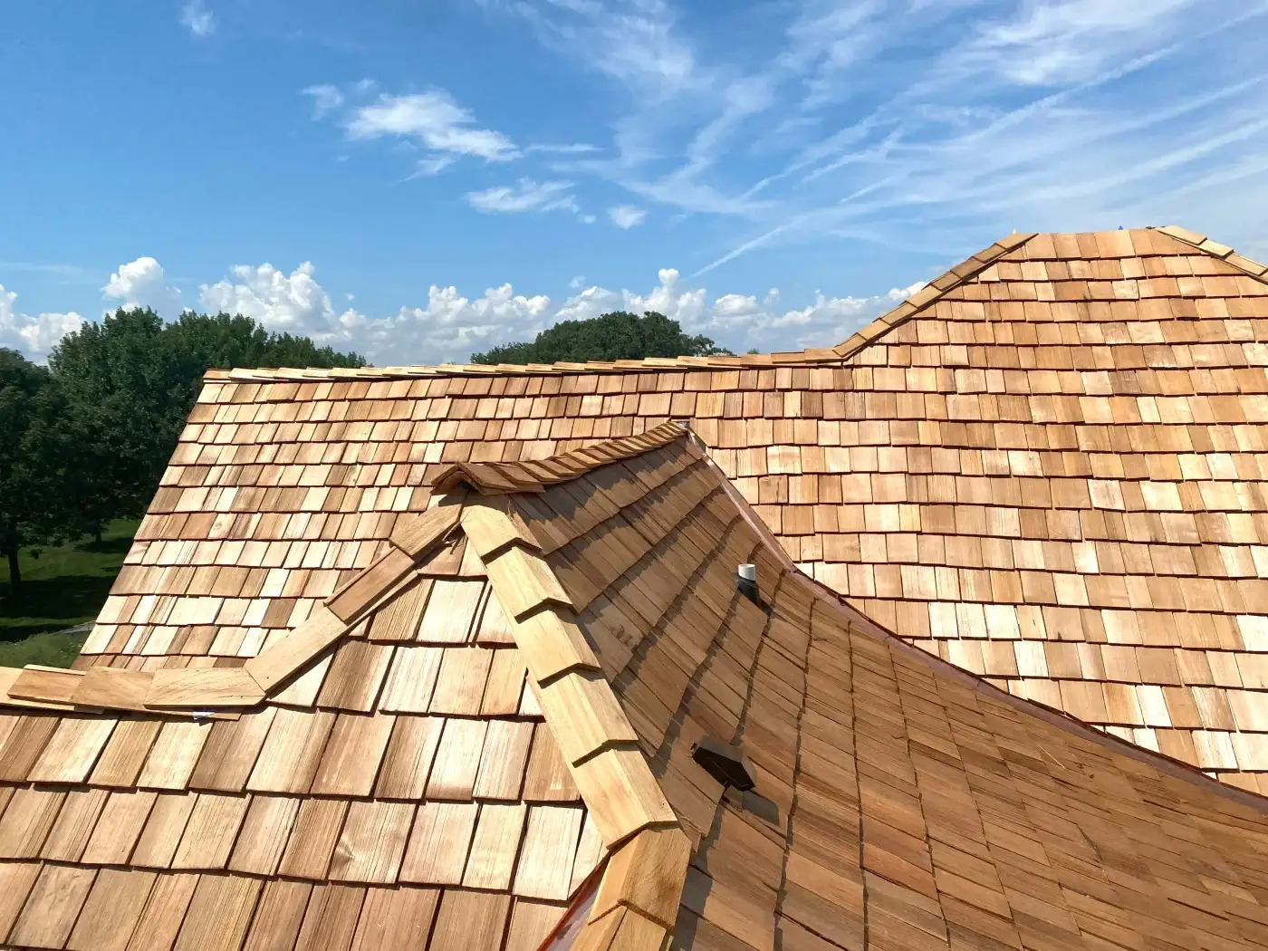 A close-up of a residential roof that recently had an aged composite cedar shake roofing system installed, showing how the different shakes lay and layer.